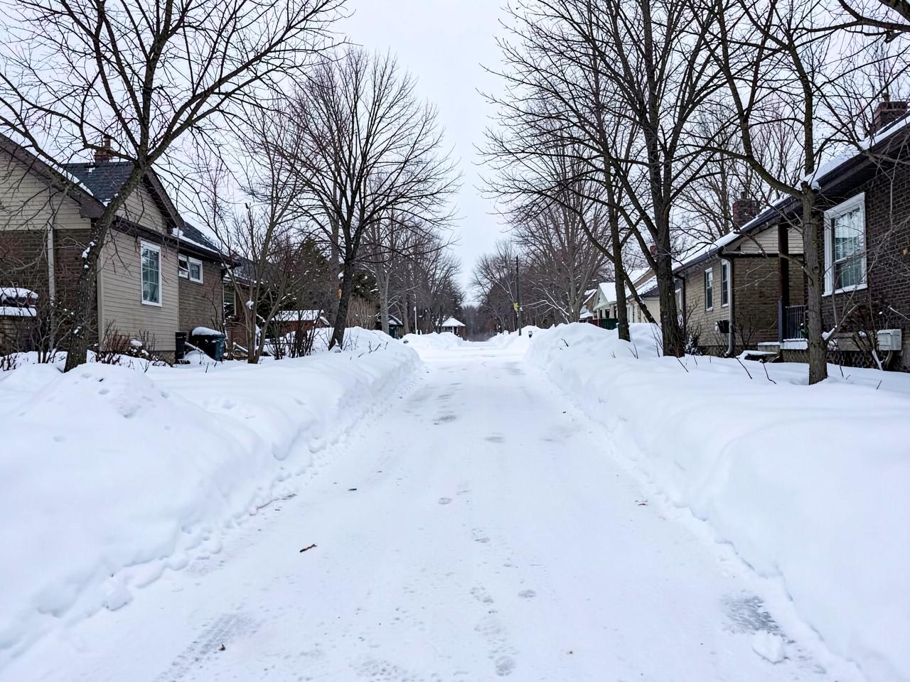 Cleared snowy residential driveway and walkway between snow banks in winter